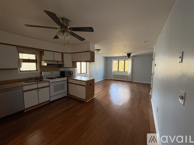 A kitchen with white cabinets and a wooden floor.