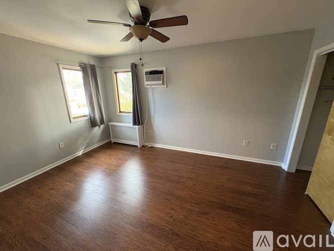 A room with a ceiling fan and wooden flooring.