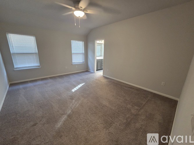 A room with a carpeted floor, a ceiling fan, and a window with blinds.