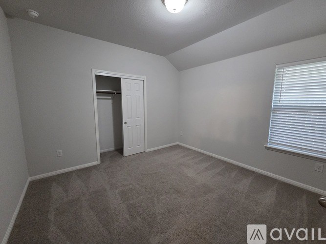 A carpeted room with a door and a window with blinds.