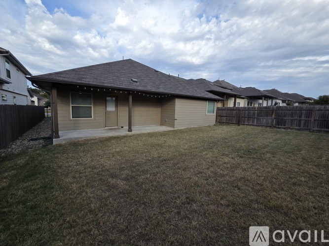 A house with a brown roof and a fence in front of it.