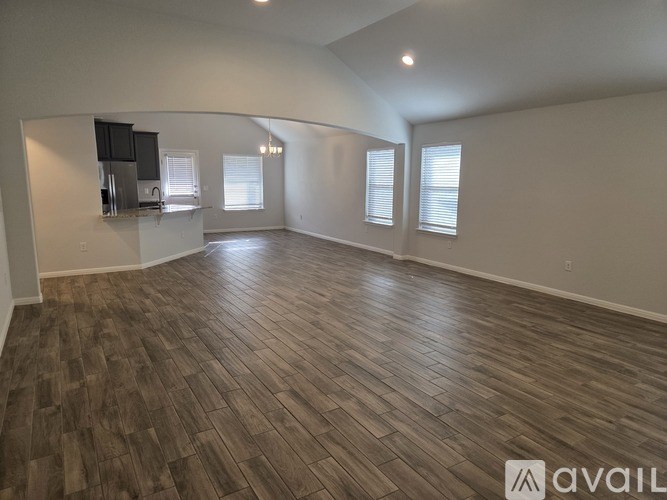 A spacious room with wooden flooring and a kitchenette in the corner.