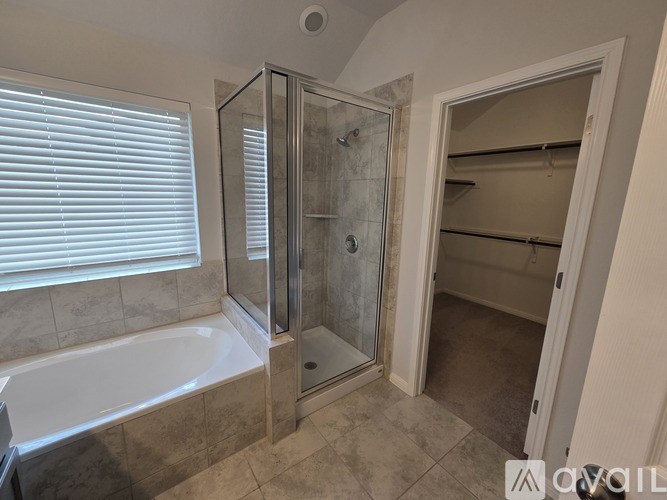 A bathroom with a glass shower door and a bathtub.