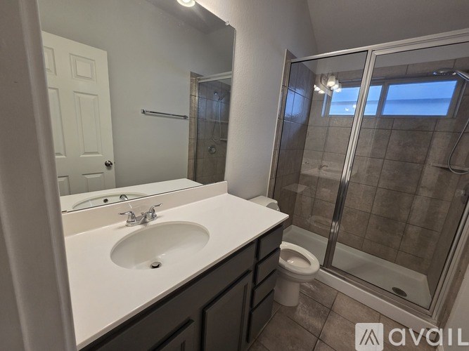 A bathroom with a sink, mirror, toilet and shower.