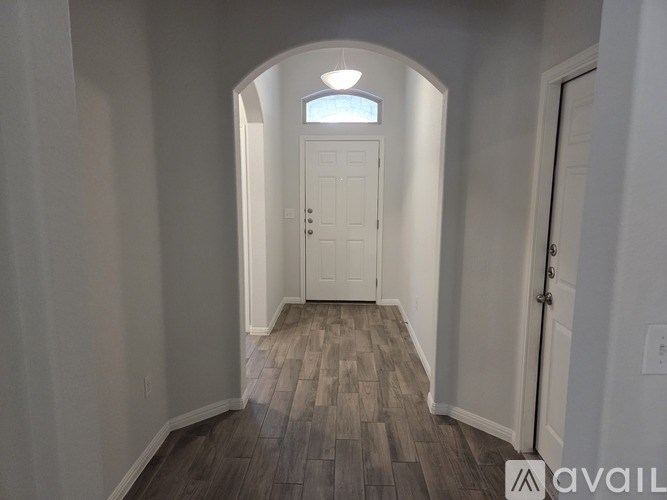 A hallway with a white door and wooden flooring.
