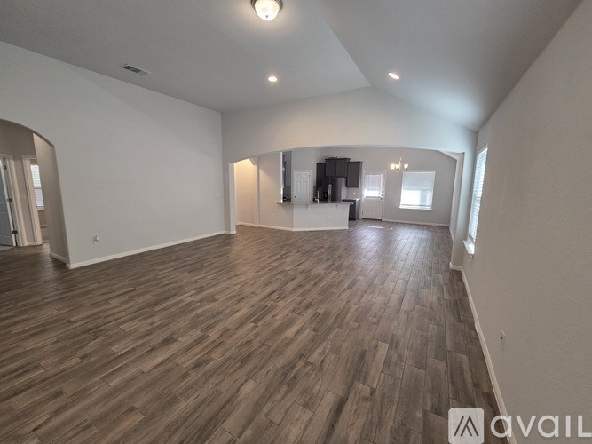 A spacious room with wooden flooring and white walls.