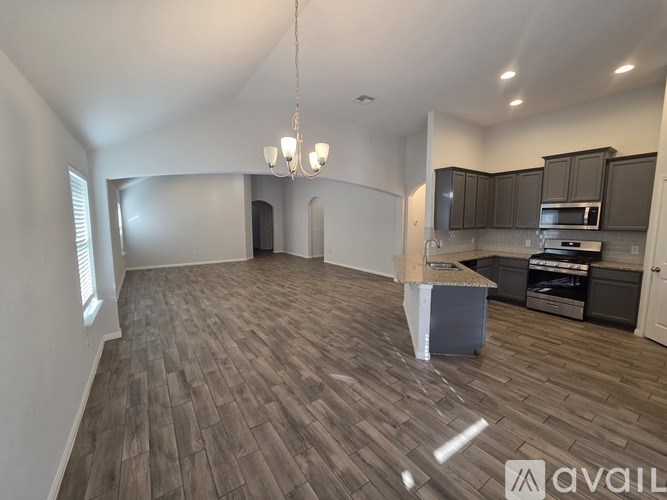 A spacious living room with a kitchen in the background.