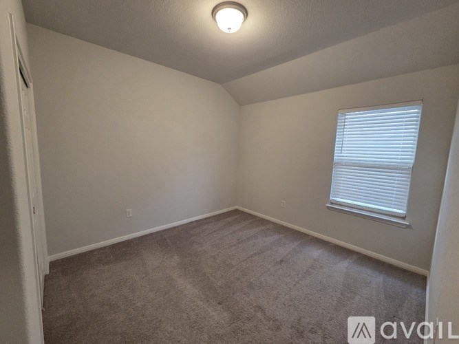 A small, empty room with a carpeted floor and a window with blinds.