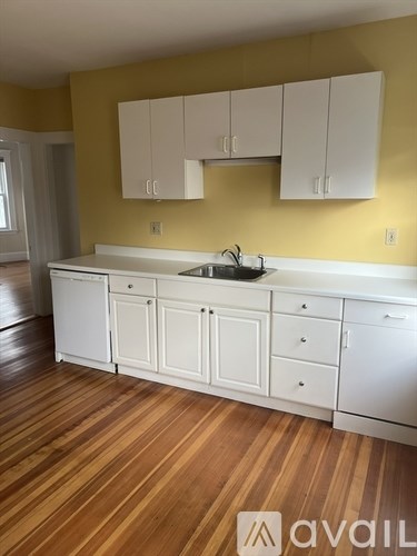 A kitchen with white cabinets and a wooden floor.