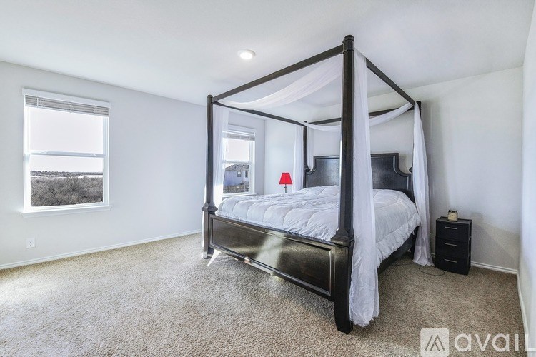 A bedroom with a four poster bed and a window overlooking a field.
