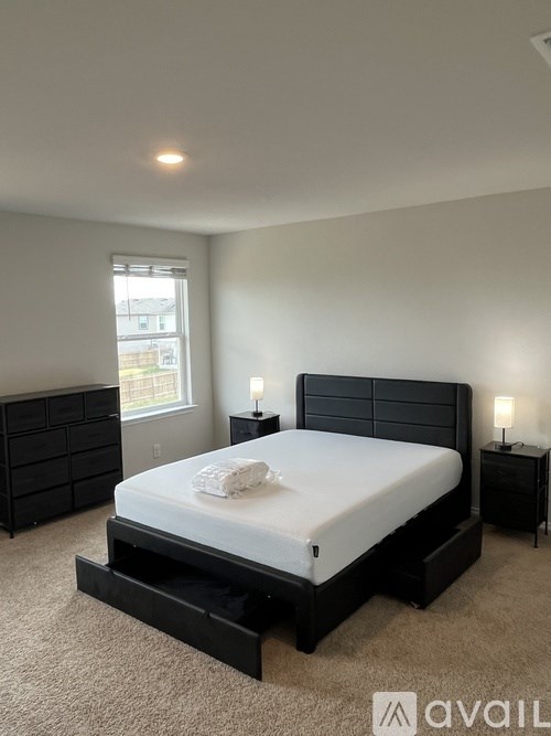 A bedroom with a large bed, nightstands, and a window.