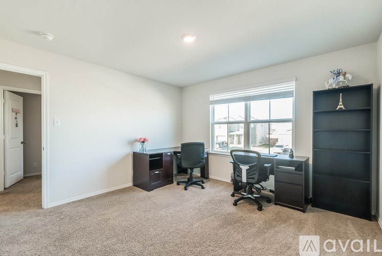 A room with a desk, chairs, and a large window.