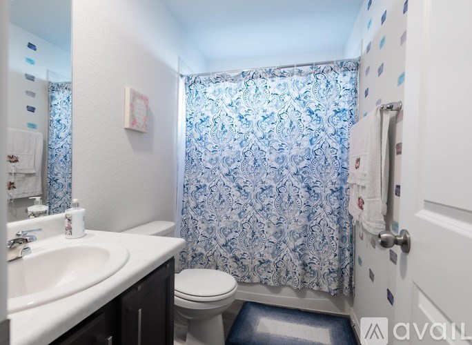A small bathroom with a toilet, sink, and shower curtain.