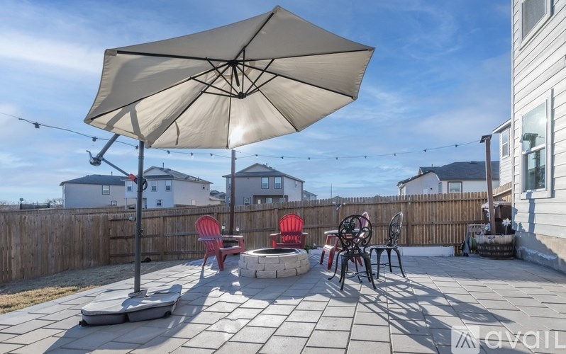 A patio with a table, chairs, and an umbrella.