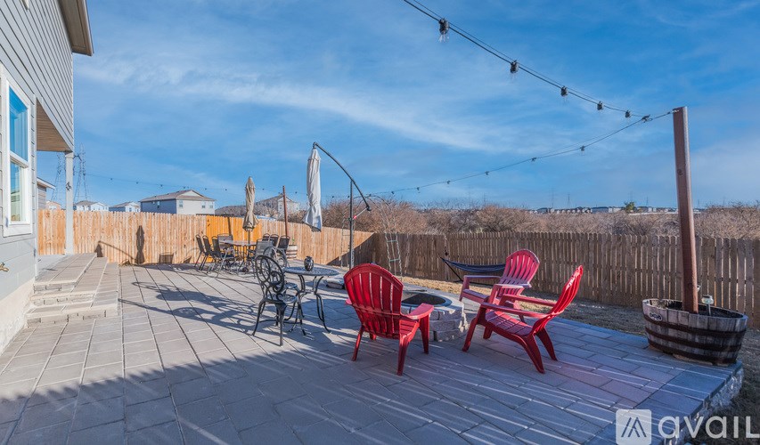 A patio with red chairs and a table is set up on a stone floor.