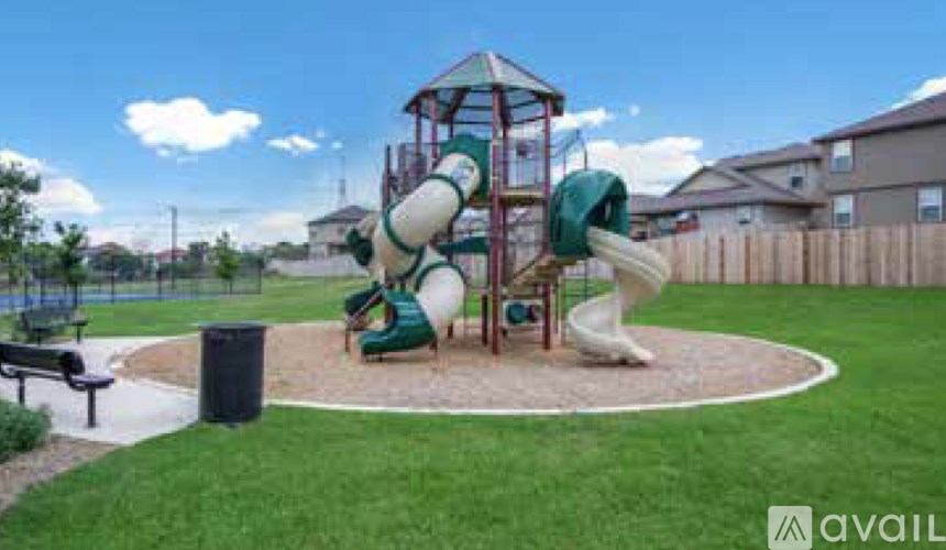 A playground with a green slide and a round sandbox.
