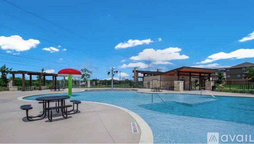 A pool with a table and chairs and a red umbrella.