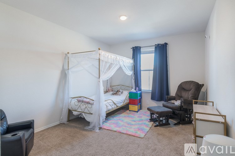 A bedroom with a canopy bed, a chair, and a small table.