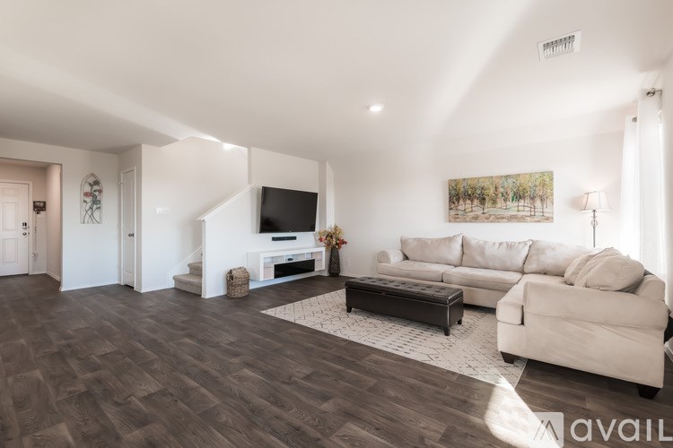 A living room with a white couch and a wooden floor.