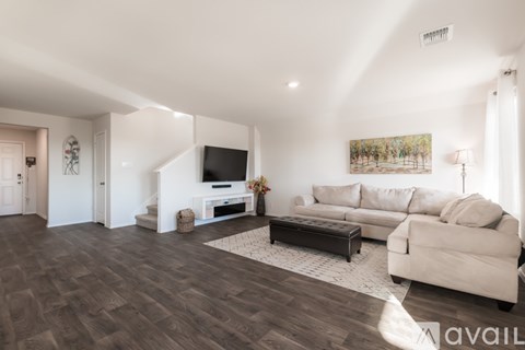 A living room with a white couch and a wooden floor.
