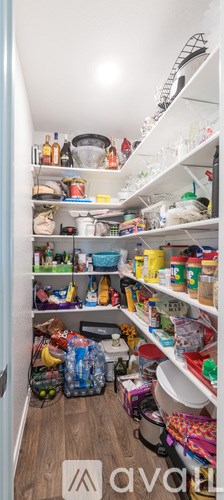 A small, cluttered kitchen with white shelves and wooden floors.