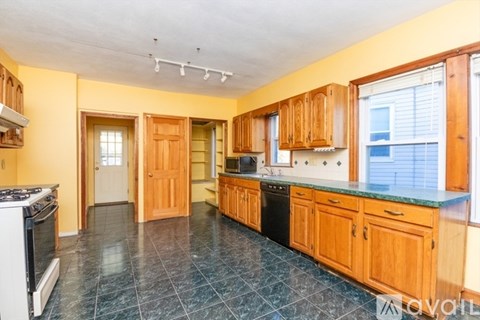 A kitchen with wooden cabinets and a black dishwasher.
