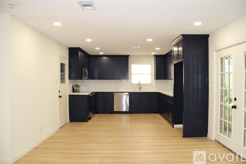 A kitchen with black cabinets and a wooden floor.