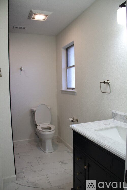 A bathroom with a toilet, sink, and window.