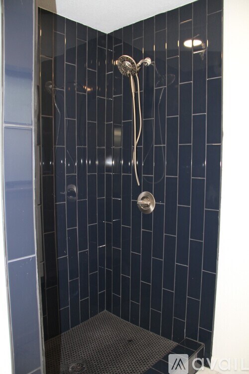 A shower with a glass door and a metal shower head.