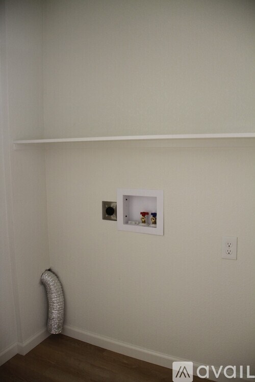 A white wall with a picture frame and a shelf above it.