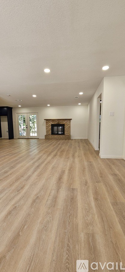 A spacious room with wooden flooring and a fireplace.