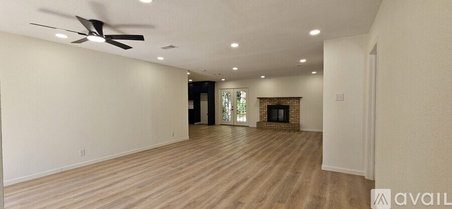 A spacious living room with a fireplace and a ceiling fan.