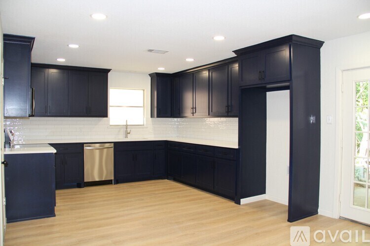 A kitchen with black cabinets and a wooden floor.