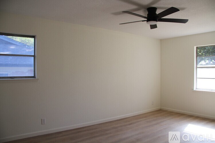 A room with a ceiling fan and two windows.