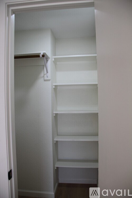 A white closet with a brown rod and shelves.