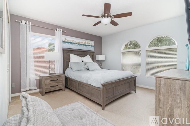 A bedroom with a bed, nightstand, and window with blinds.