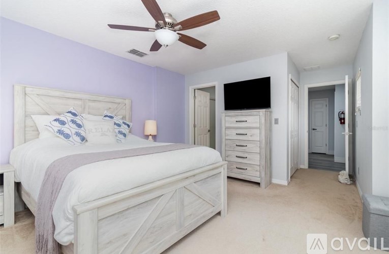 A bedroom with a large bed and a ceiling fan.