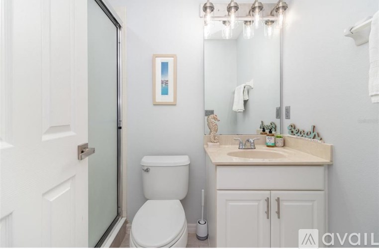 A white toilet is in a small bathroom with a white sink and a white cabinet.