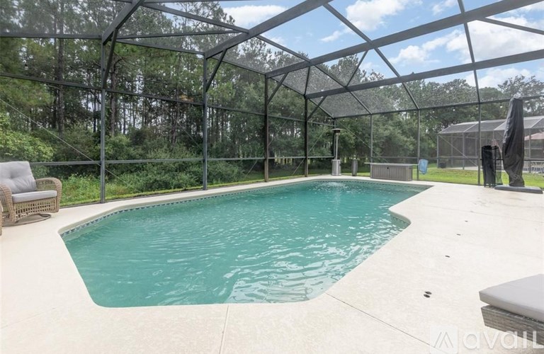 A pool enclosed by a black metal fence with trees in the background.