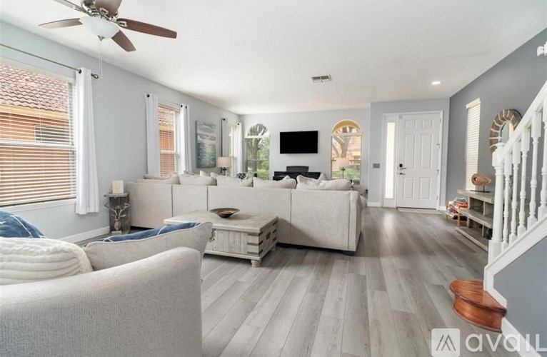 A living room with a white couch and a television on the wall.