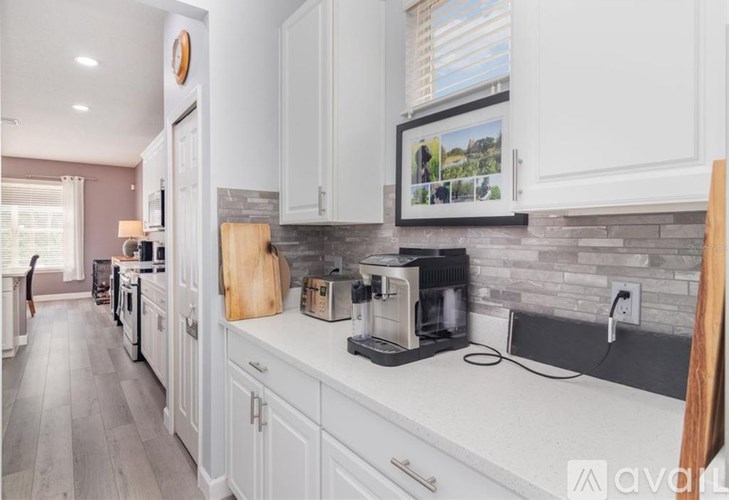 A kitchen with white cabinets and a wooden cutting board on the counter.