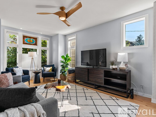 A living room with a grey couch, a wooden cabinet, and a ceiling fan.