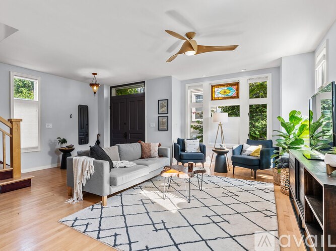 A living room with a grey couch, a black door, and a ceiling fan.