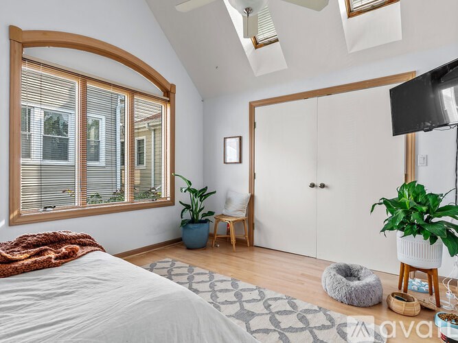 A bedroom with a large bed and a window with blinds.