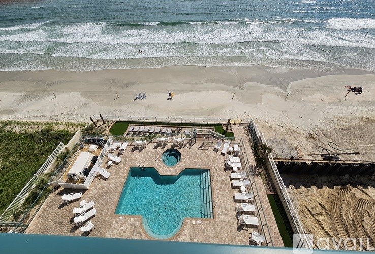 An aerial view of a beach with a swimming pool and lounge chairs.