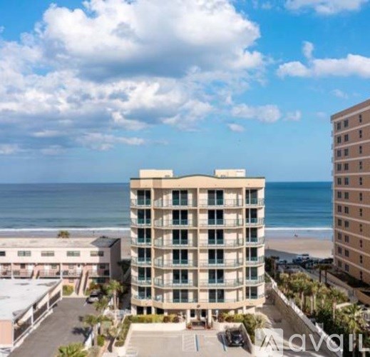 A tall building with balconies overlooks a beach.