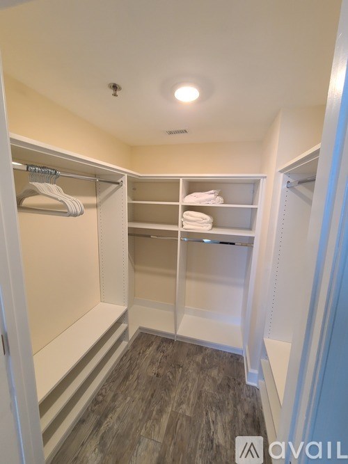 A walk-in closet with white shelves and a grey floor.