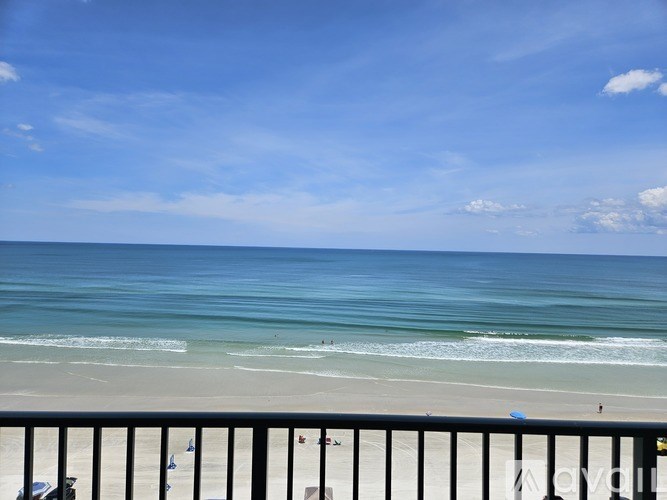 A beach scene with people on the sand and the ocean in the distance.