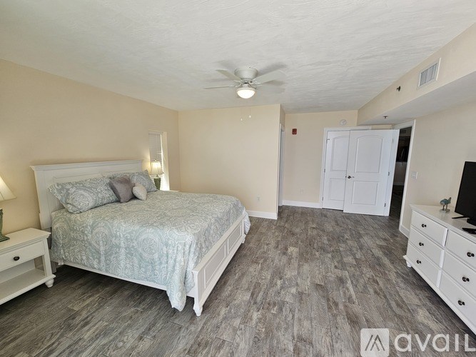 A bedroom with a bed, dresser, and ceiling fan.