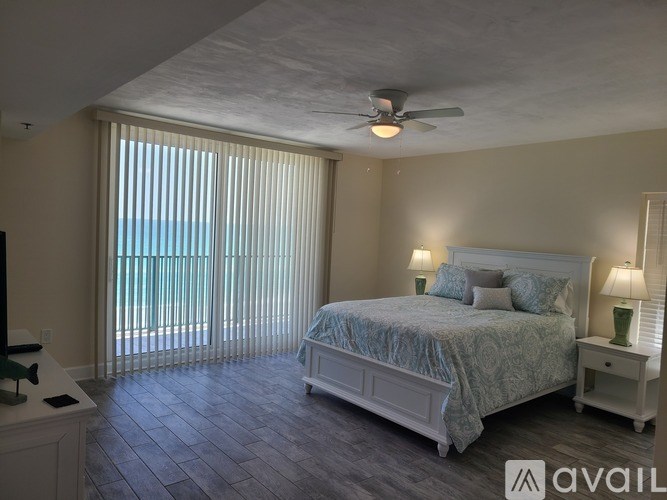 A bedroom with a large bed, a ceiling fan, and a sliding glass door.